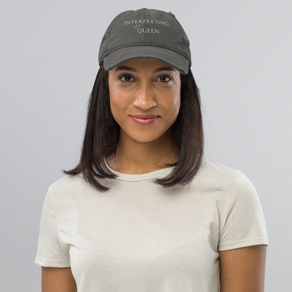 Gray distressed baseball cap with white text "Interpreting Queen" with a small crown on top of the letter Q in Queen.